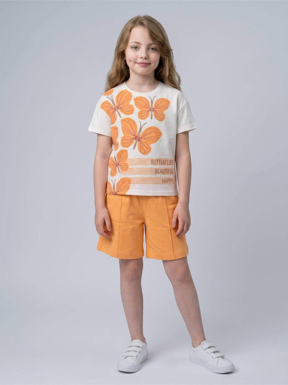 Girl wearing The Nile Luxuries white butterfly graphic t-shirt and orange shorts set with front seam detailing.