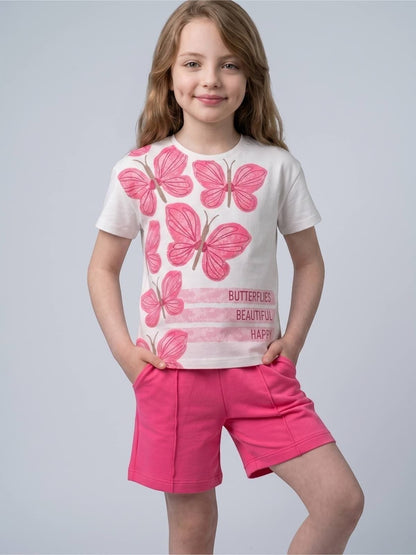 Young girl wearing a The Nile Luxuries white t-shirt with pink butterfly graphics and matching pink shorts.