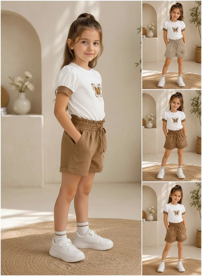 The Nile Luxuries girls white puff-sleeve butterfly t-shirt and brown paper-bag waist shorts set with white sneakers.
