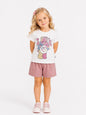 Girl wearing The Nile Luxuries white Care Bears graphic cotton t-shirt and mauve shorts against a white background.