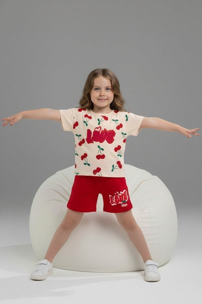 Girl wearing The Nile Luxuries cream cherry print t-shirt and red shorts with LOVE graphic on a white bean bag chair.