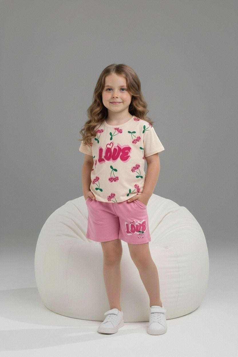 Girl wearing The Nile Luxuries cream cherry print t-shirt and pink shorts with LOVE graphic on a white bean bag chair.