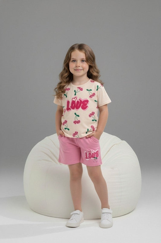 Girl wearing The Nile Luxuries cream cherry print t-shirt and pink shorts with LOVE graphic on a white bean bag chair.