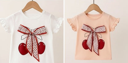 The Nile Luxuries girls' white cotton t-shirt with cherry graphic, bow, and ruffled sleeves.