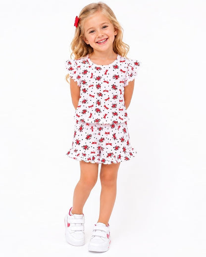 The Nile Luxuries girls' white lounge set with red dragonfly print, flutter sleeves, and ruffled shorts on a girl.