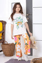 The Nile Luxuries girls lounge set with white graphic t-shirt and orange floral wide-leg pants on a young girl.