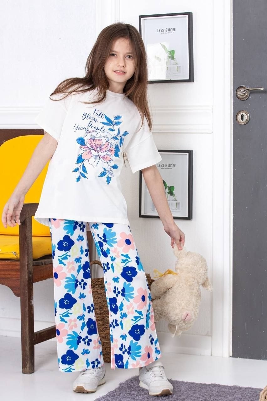 The Nile Luxuries girls lounge set with white graphic t-shirt and floral wide-leg trousers worn by a young girl.
