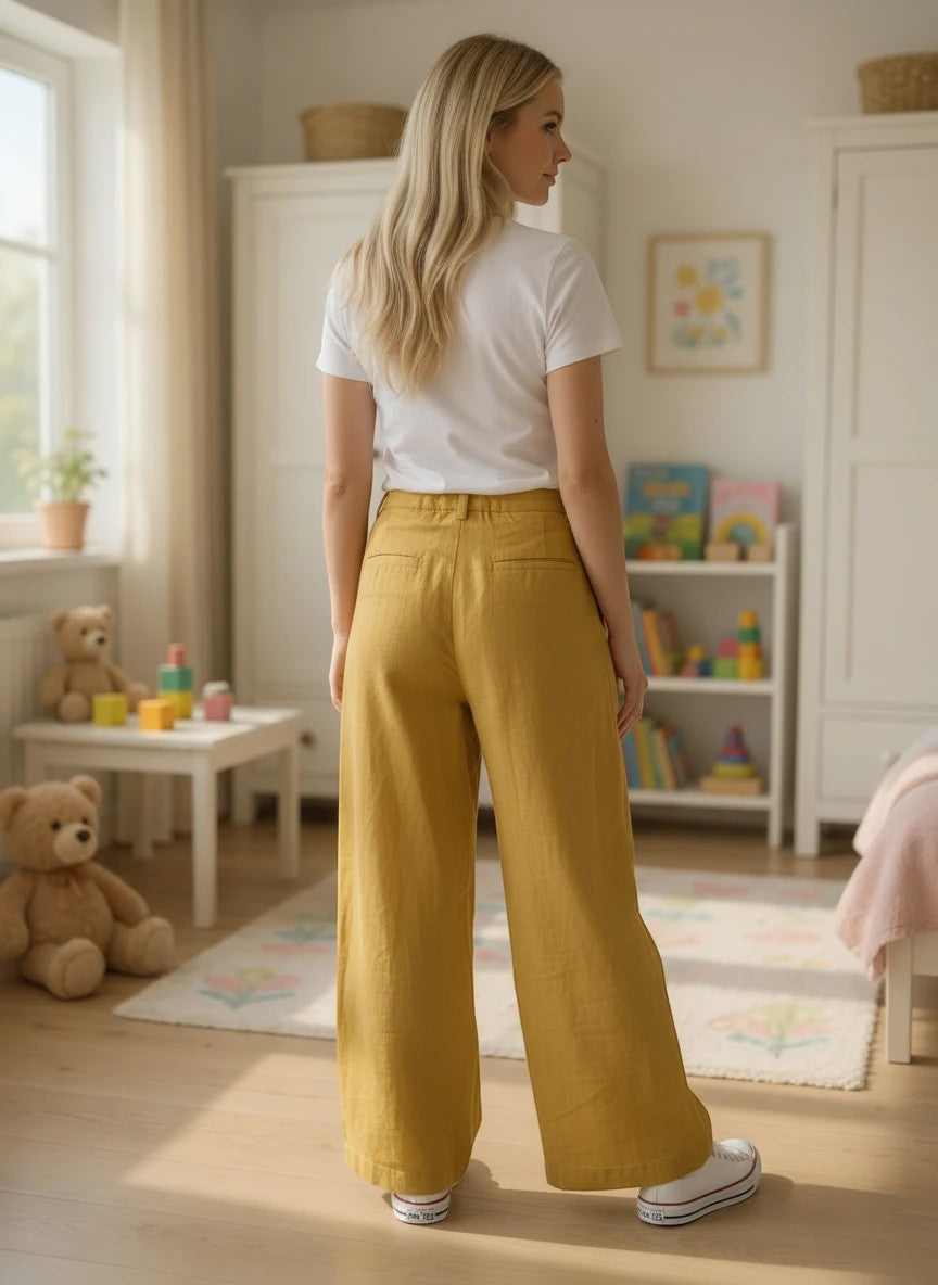 The Nile Luxuries girls outfit featuring a white t-shirt and yellow wide-leg pants in a bright nursery setting.