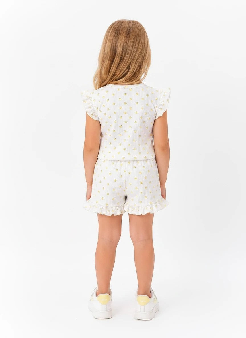 The Nile Luxuries girls white lounge set with yellow floral print, flutter sleeves, and ruffled hem shorts, back view.