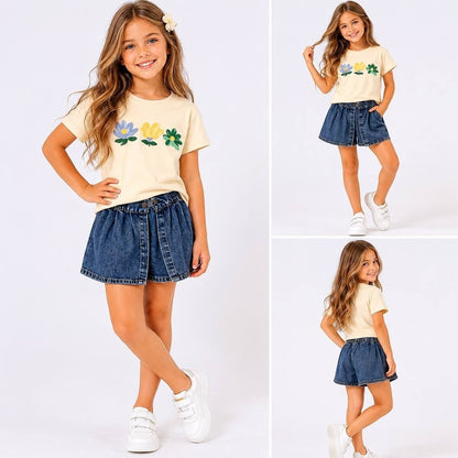 Girl wearing The Nile Luxuries floral graphic t-shirt and denim skort set with white sneakers on a white background.
