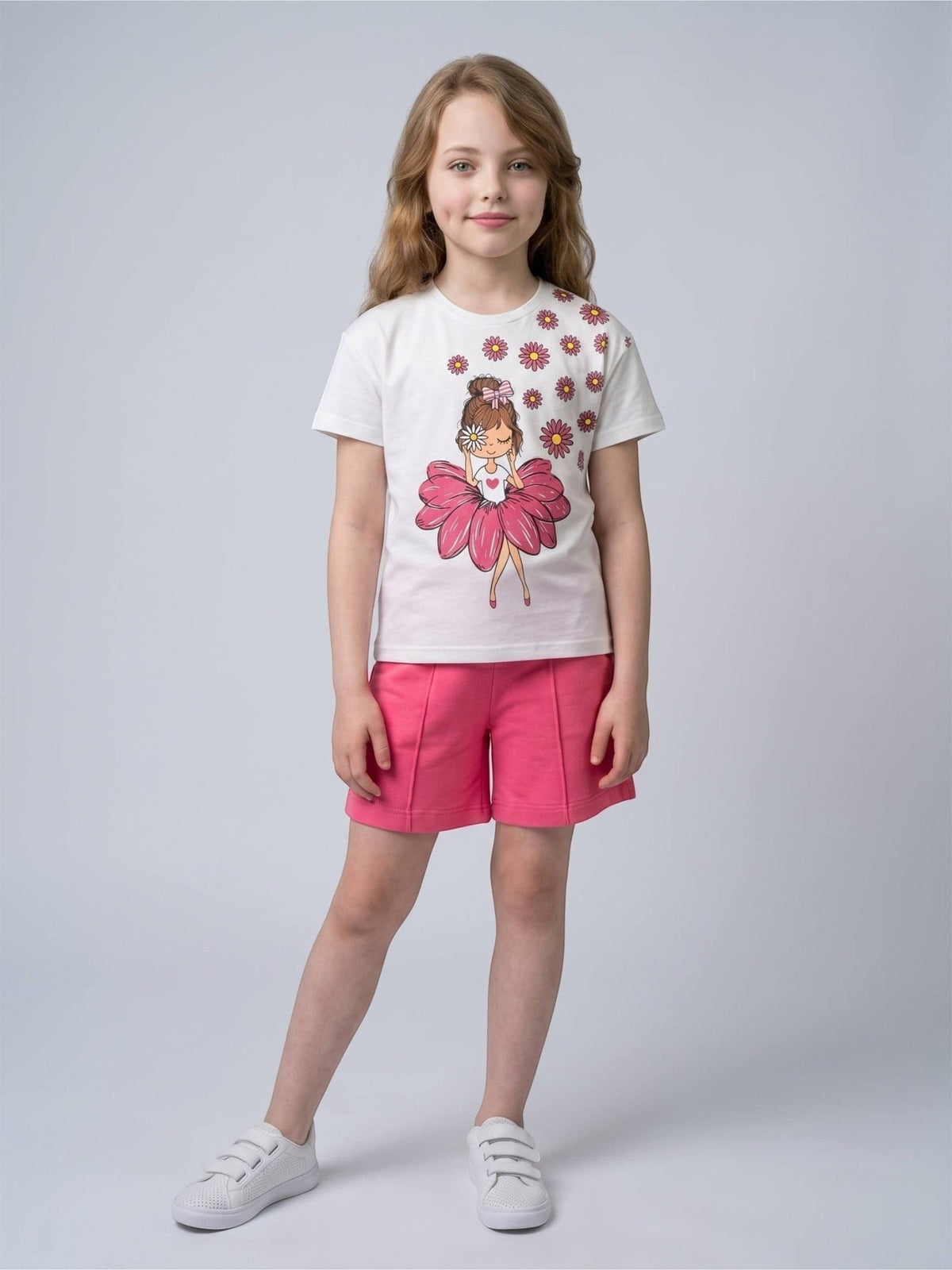 The Nile Luxuries girls white graphic t-shirt with daisy print and pink shorts set worn by a young girl.