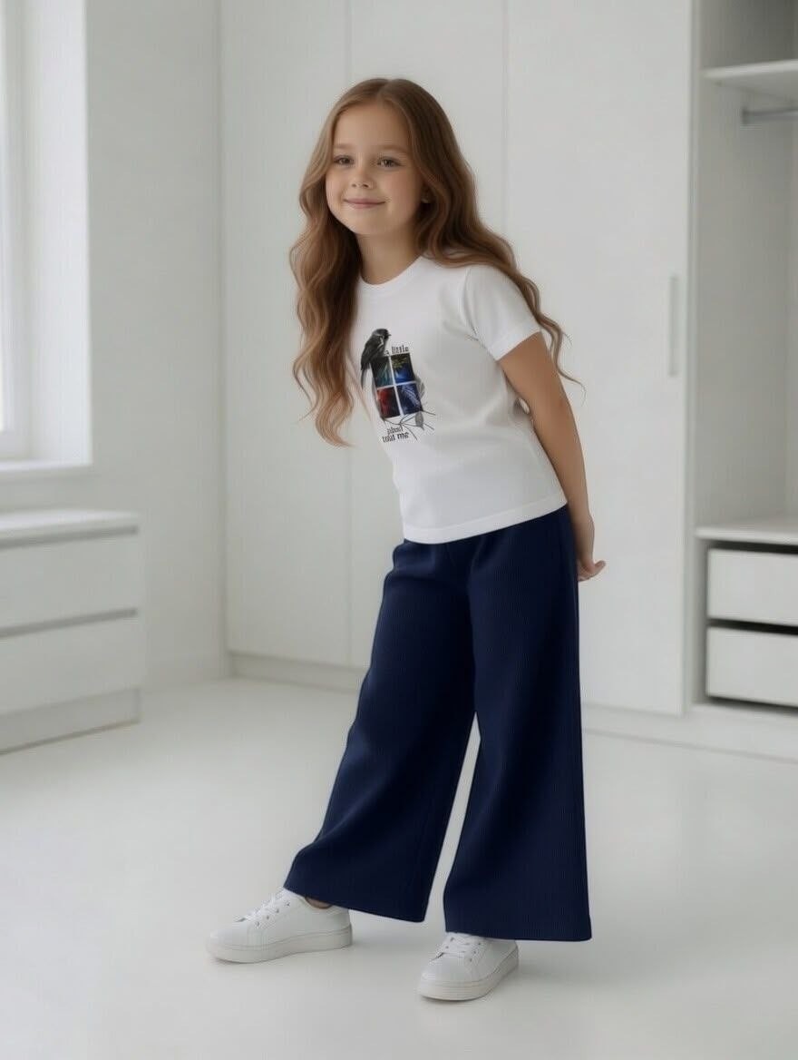 Girl wearing The Nile Luxuries white bird graphic t-shirt and navy blue ribbed wide-leg trousers in a bright room.