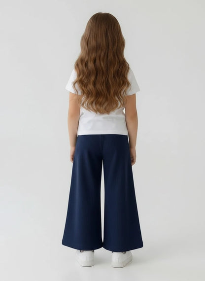 Girl wearing The Nile Luxuries white t-shirt and navy blue ribbed wide-leg trousers, back view.