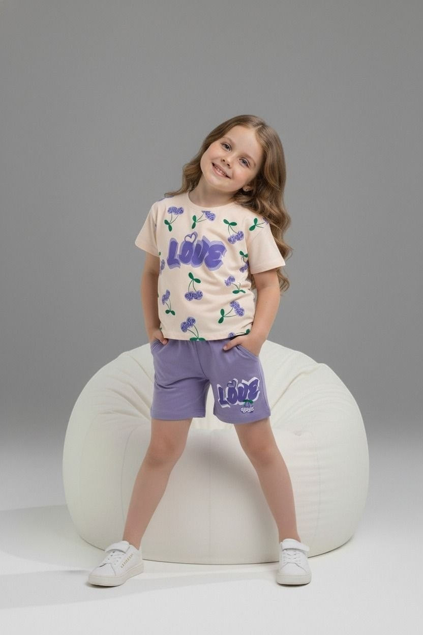 Young girl wearing The Nile Luxuries cream cherry print t-shirt and purple shorts set with LOVE graphic.