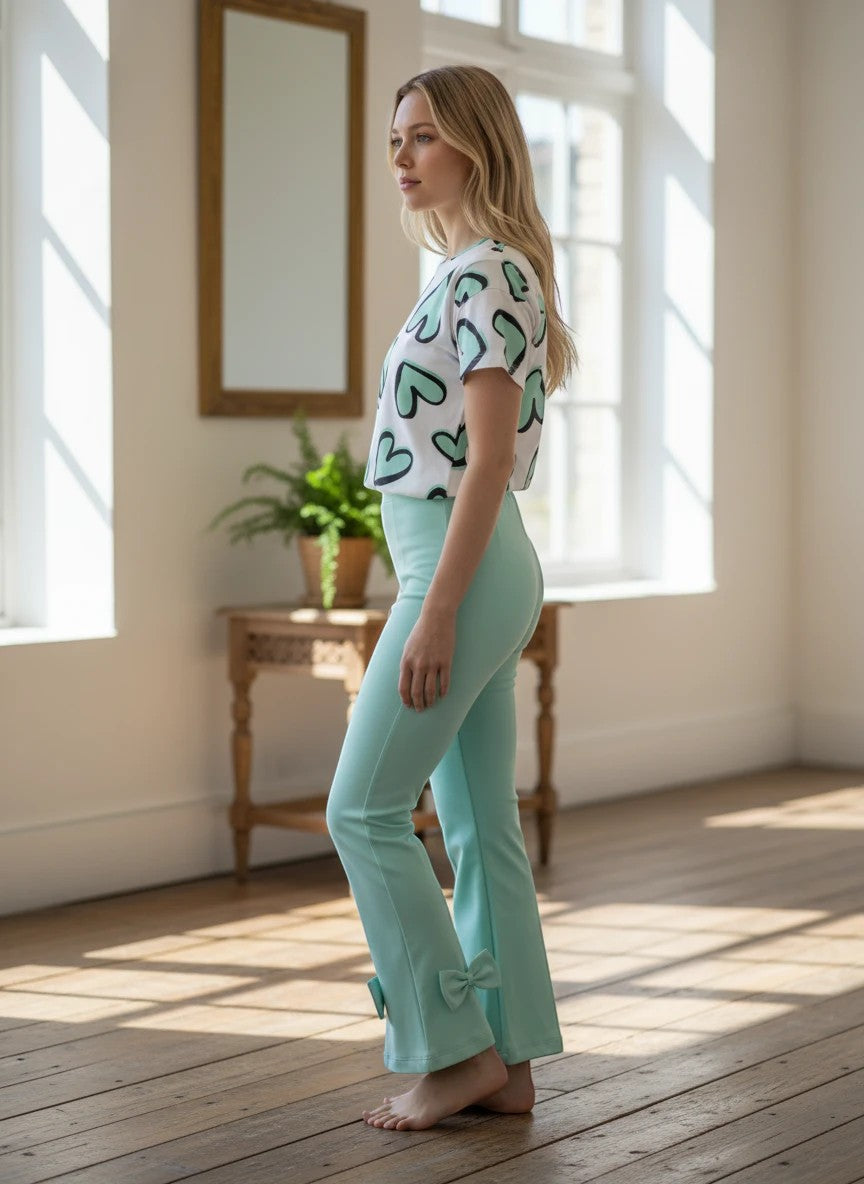 The Nile Luxuries girls heart print t-shirt and mint green flared trousers with bow hem detail on a model.