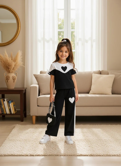 The Nile Luxuries girls black and white heart graphic short sleeve top and wide leg pants set with tie sleeves.
