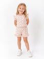 The Nile Luxuries girls' beige lounge set with red heart print, flutter sleeves, and ruffled shorts on a smiling girl.
