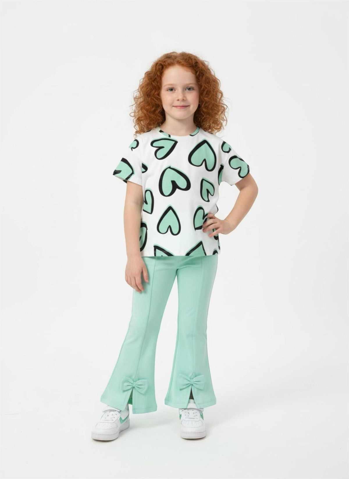 Girl wearing The Nile Luxuries heart print t-shirt and mint green flared trousers with bow hem details.
