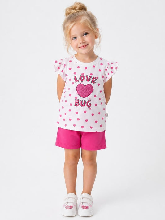 Young girl wearing The Nile Luxuries white heart-print flutter sleeve t-shirt and pink shorts set.
