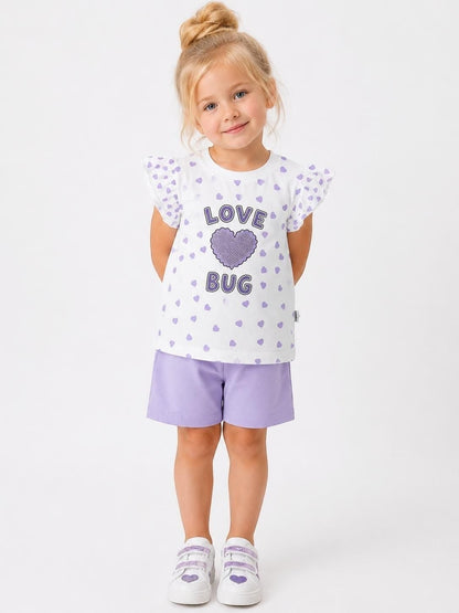 Young girl wearing The Nile Luxuries white flutter-sleeve t-shirt with purple heart print and matching purple shorts.
