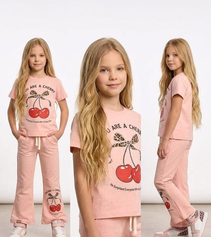 The Nile Luxuries girls pink cotton-blend lounge set with cherry graphic t-shirt and flared pants on a young model.