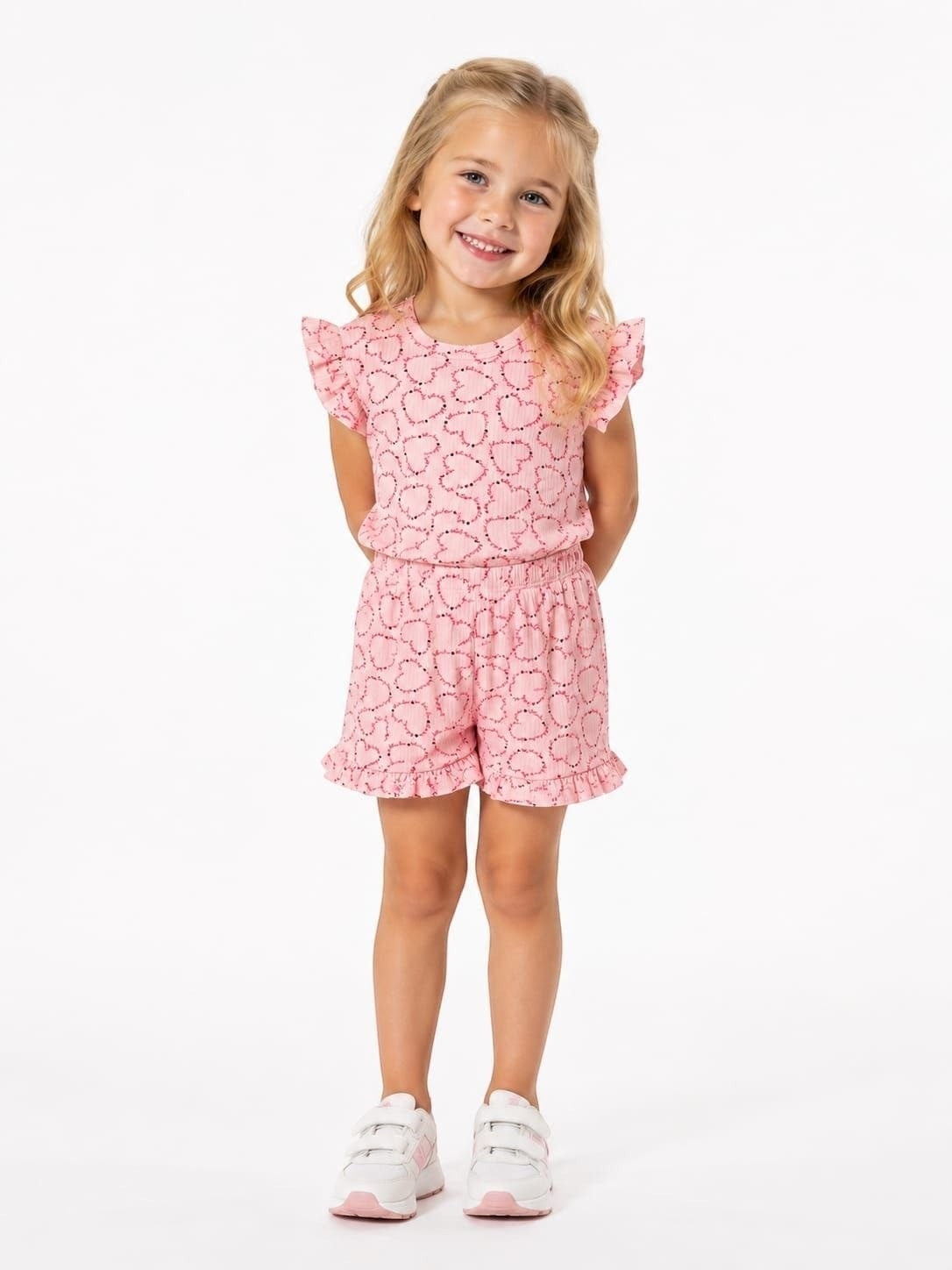 The Nile Luxuries girls pink heart print lounge set with flutter sleeves and ruffled shorts on a smiling young girl