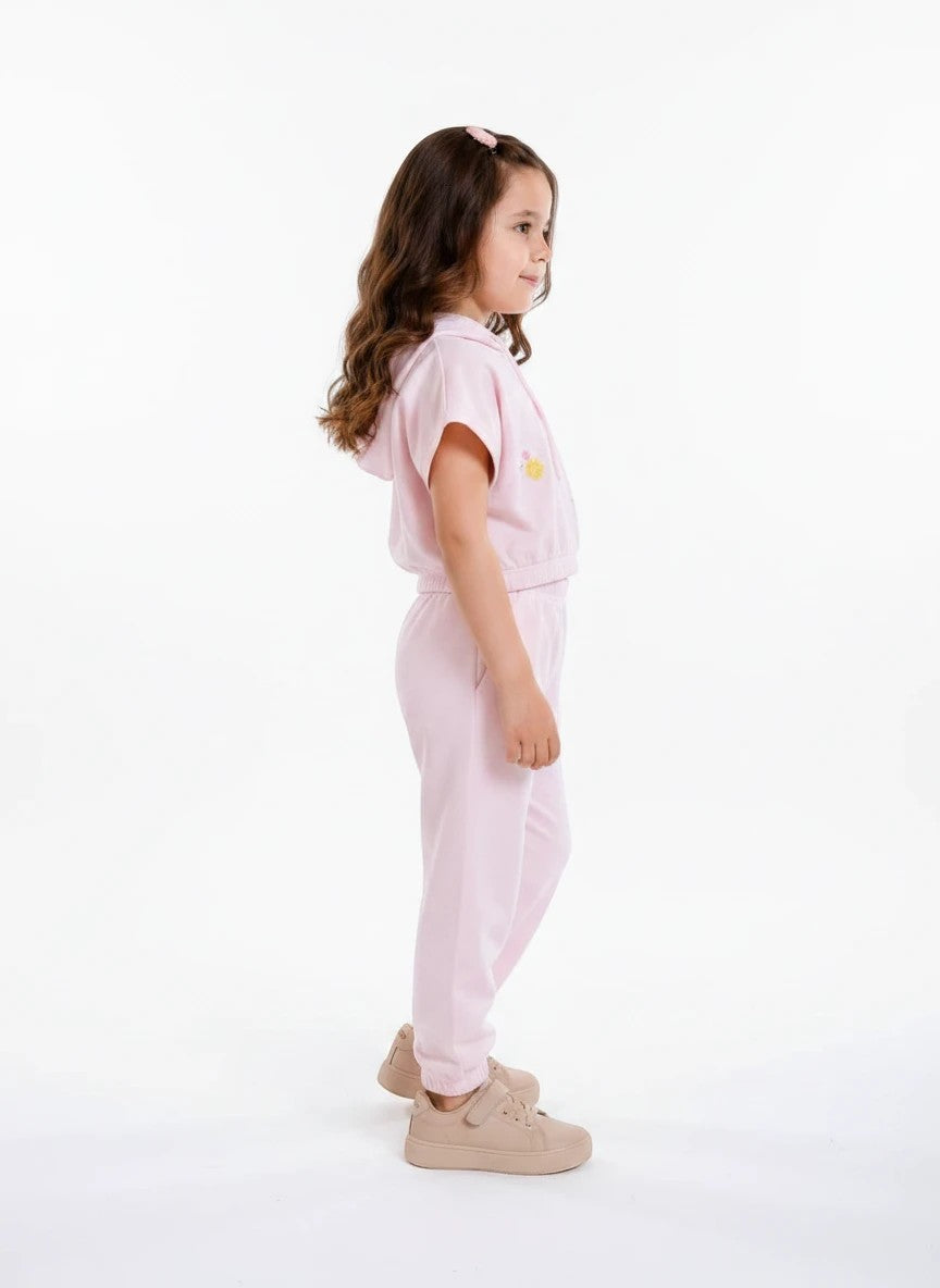 A young girl wearing The Nile Luxuries light pink short-sleeve hoodie and matching jogger lounge set with floral detail.