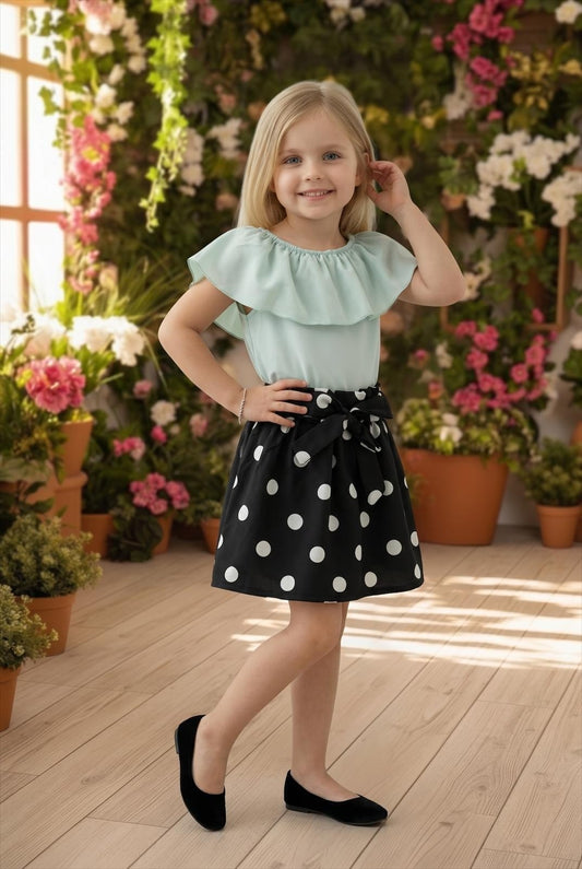 The Nile Luxuries girls' mint green ruffled top with black polka dot skirt and bow detail.