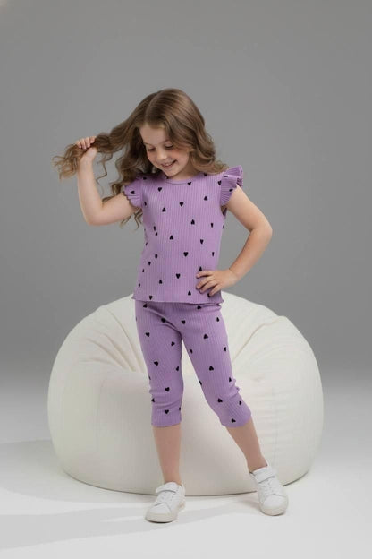 Girl wearing The Nile Luxuries purple ribbed lounge set with black heart print, flutter sleeves, and cropped leggings.
