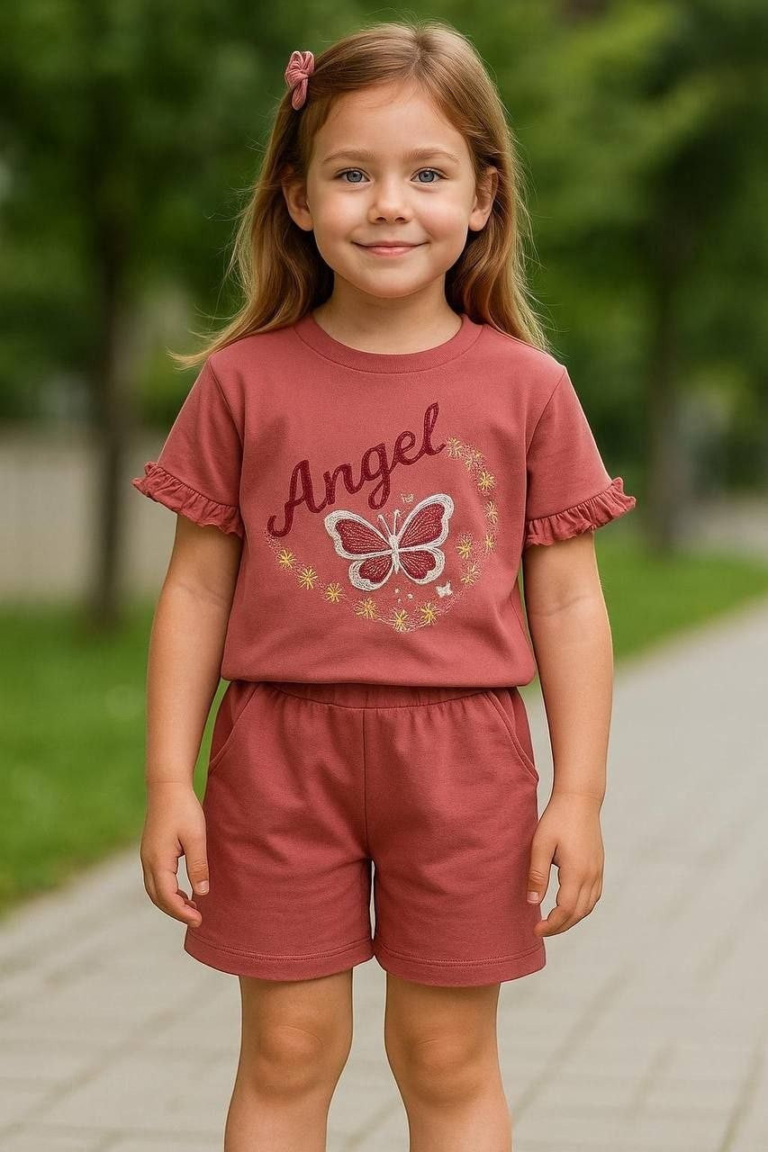The Nile Luxuries girl's dusty rose short set with ruffled sleeves, Angel graphic, and butterfly motif on a young girl.
