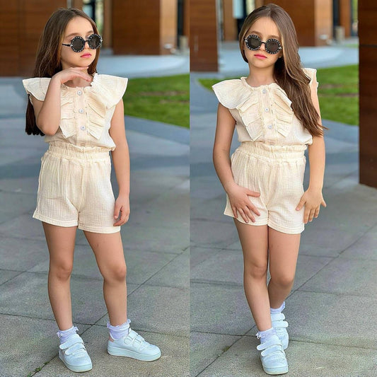 Girl wearing The Nile Luxuries beige ruffled sleeveless top and matching elastic shorts with white sneakers.
