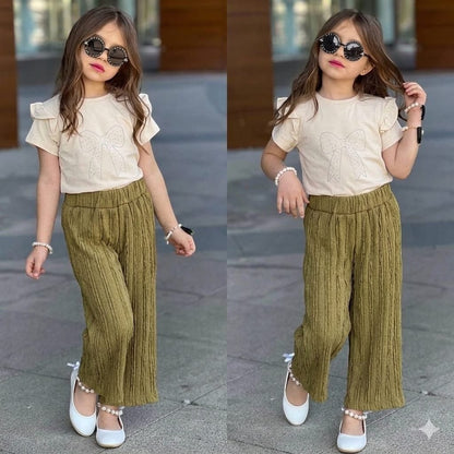 Girl wearing The Nile Luxuries beige ruffle sleeve top with sparkling bow and olive green textured trousers.