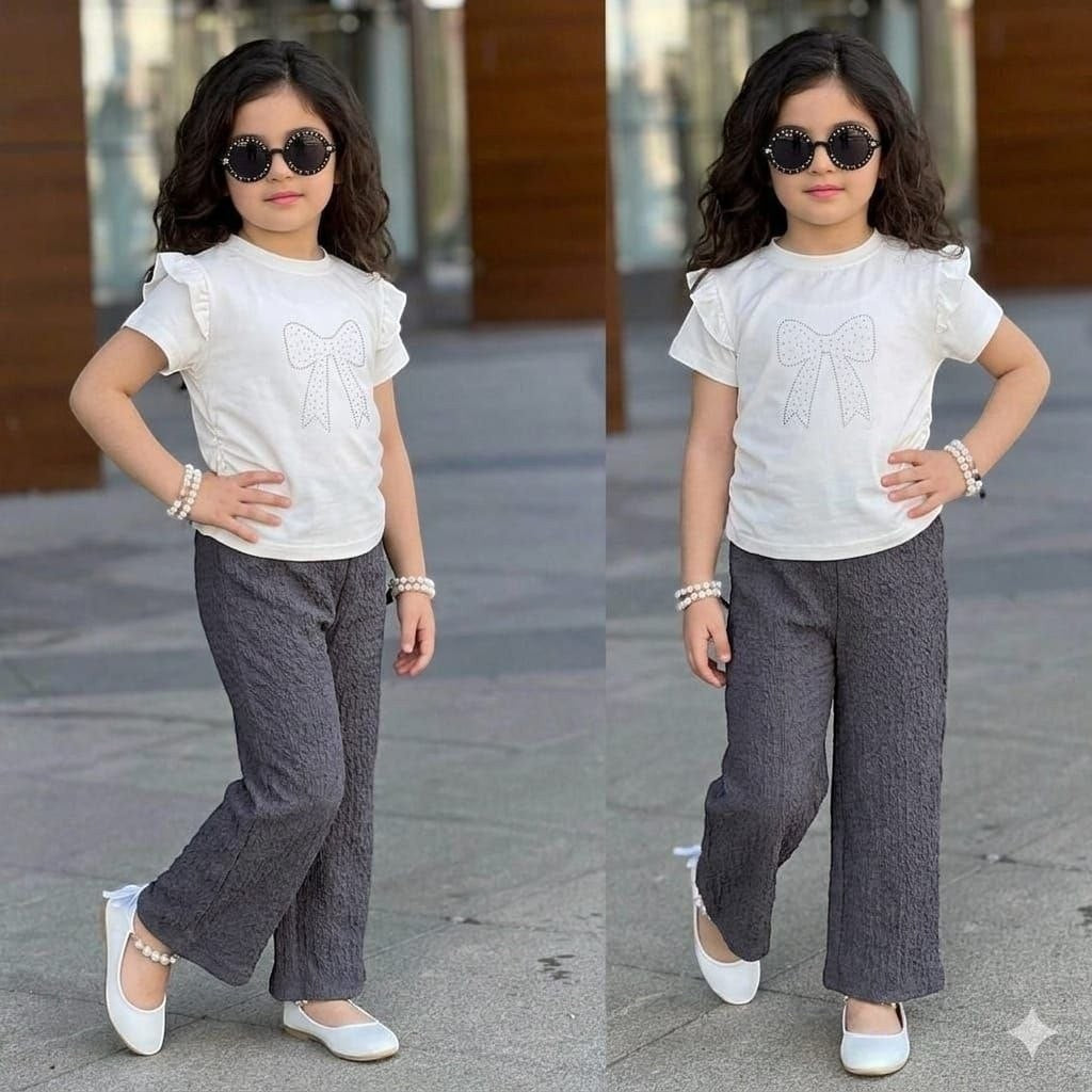 Girl wearing The Nile Luxuries white ruffle sleeve top with sparkling bow and grey textured trousers with white flats.