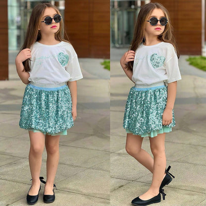 The Nile Luxuries girls outfit with a white t-shirt and a sparkly turquoise sequin skirt, worn by a young girl.