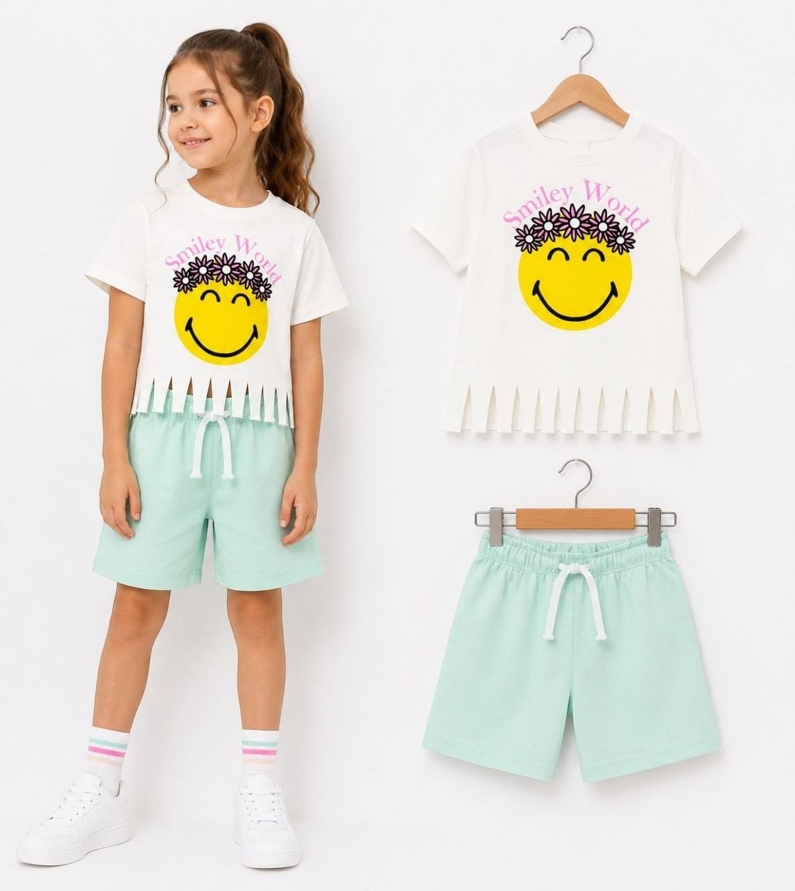The Nile Luxuries girls' white t-shirt with smiley face graphic and fringed hem, paired with mint green shorts.