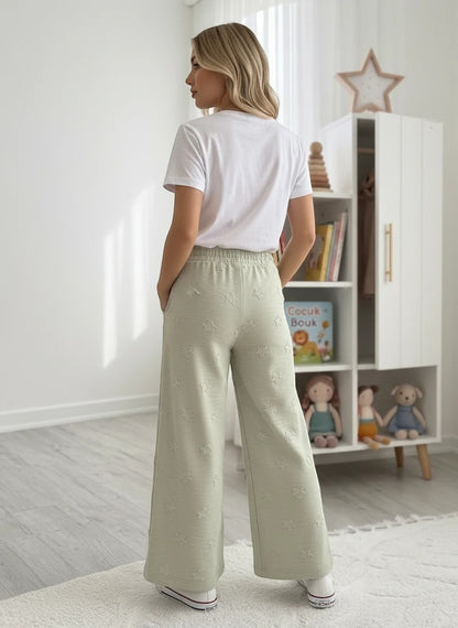 The Nile Luxuries girls' set with white t-shirt and sage green wide-leg pants featuring textured star patterns.