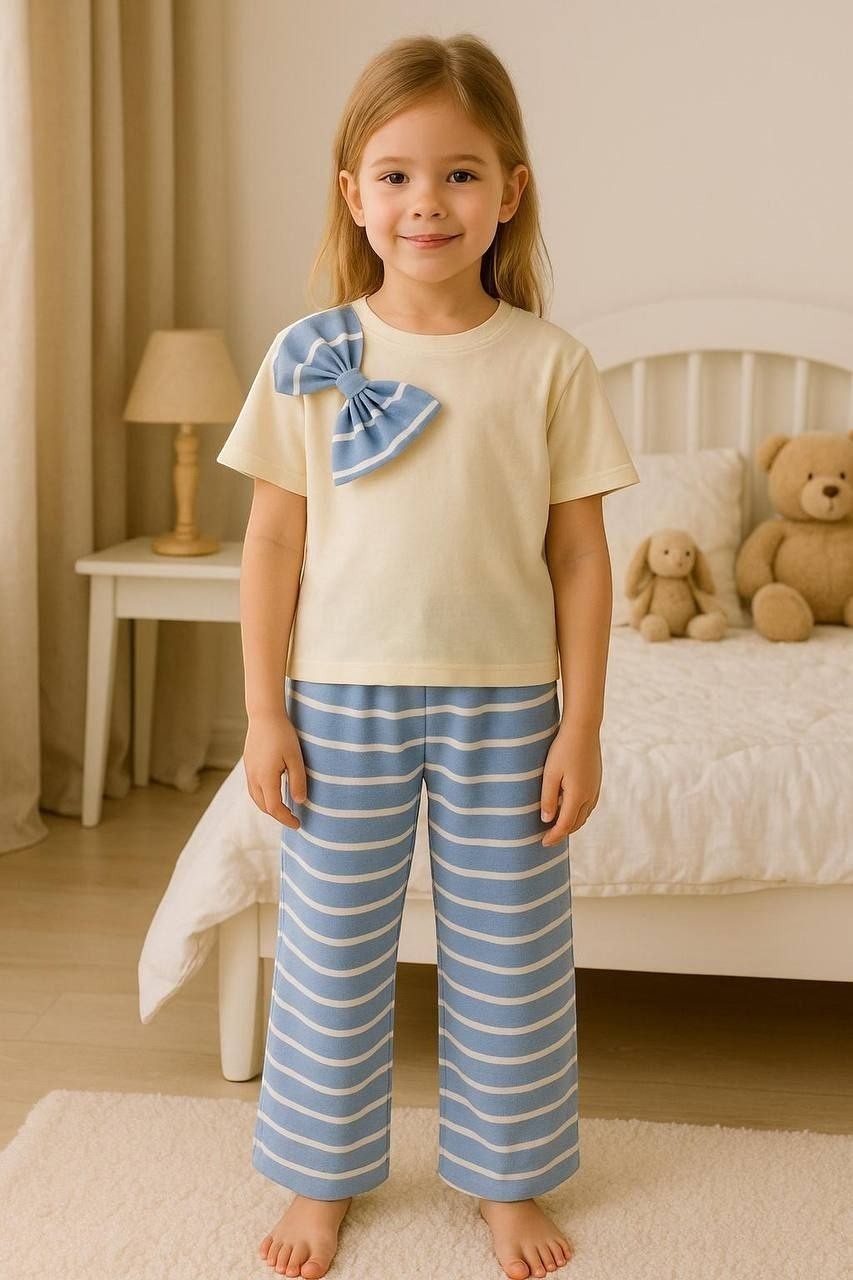 The Nile Luxuries girls pajama set with a cream crew-neck top, blue striped bow, and matching blue striped wide-leg pants.