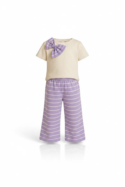 The Nile Luxuries girls two-piece pajama set with a cream crew-neck top, purple bow detail, and striped wide-leg pants.