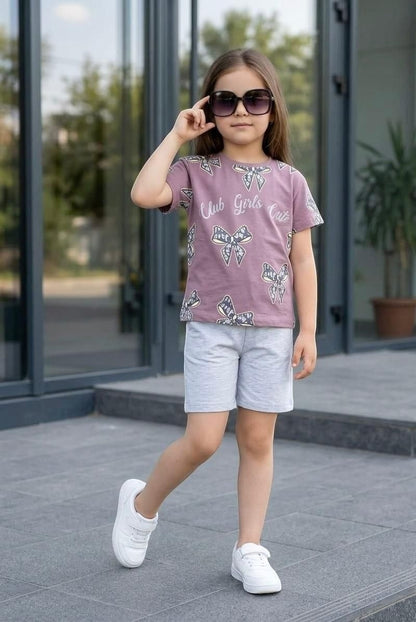 The Nile Luxuries girls' mauve short-sleeve t-shirt with bow print and grey shorts set worn by a young girl.