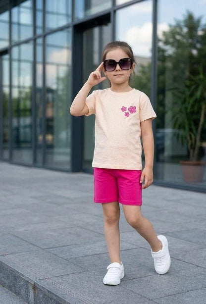The Nile Luxuries girls summer outfit with a peach polka dot t-shirt, floral appliqué, and bright pink shorts.