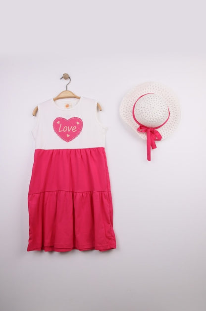 The Nile Luxuries white sleeveless tiered dress with pink heart graphic and matching pink hat.