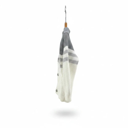 The Nile Luxuries infant knit cardigan in white and grey with button closure hanging on a wooden hanger