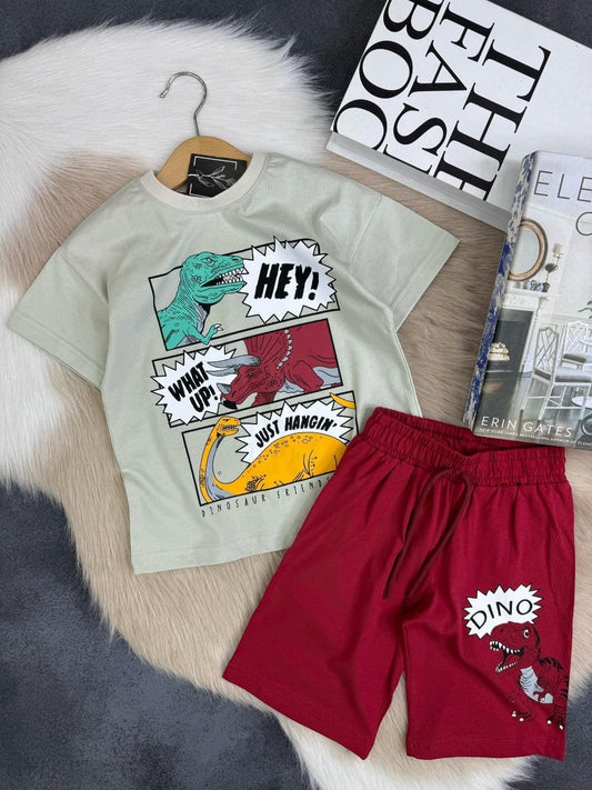The Nile Luxuries kids' light beige t-shirt with comic-style dinosaur graphics and red shorts with a dinosaur print. Cotton blend.
