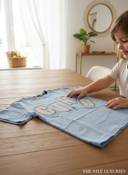 The Nile Luxuries light blue cotton t-shirt for kids with a graphic print.