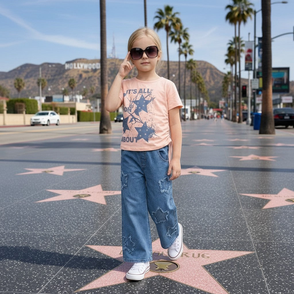 The Nile Luxuries: Girl in peach t-shirt with star graphic and wide-leg denim jeans with star patches.