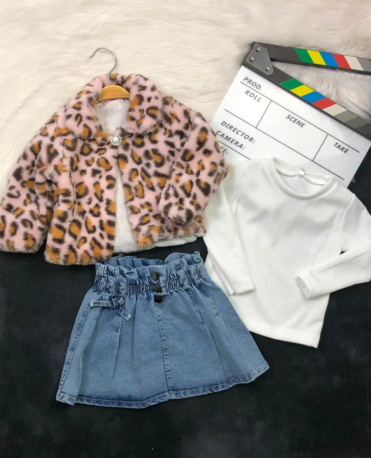 The Nile Luxuries three-piece outfit featuring a pink leopard faux fur jacket, white ribbed top, and denim skirt.