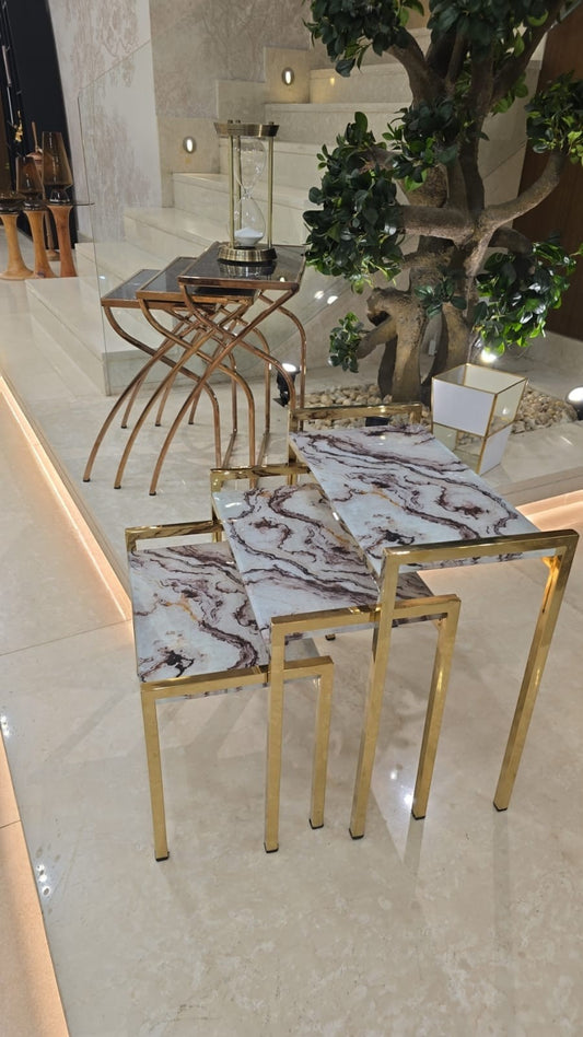 The Nile Luxuries set of 3 nesting tables with white and burgundy marble-effect tops and gold metal frames.