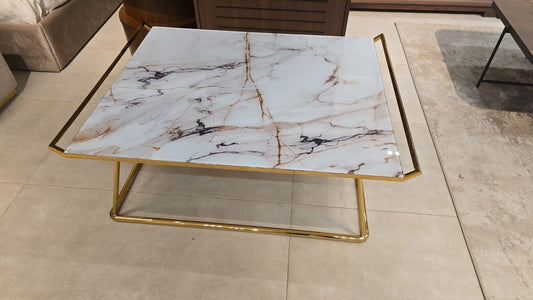 The Nile Luxuries modern accent table with white marble-look top and gold geometric base.