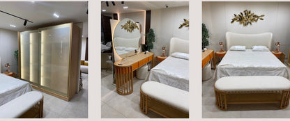 The Nile Luxuries modern bedroom set: upholstered bed, vanity with orange drawers, sliding wardrobe, rattan bench, and metallic wall art.