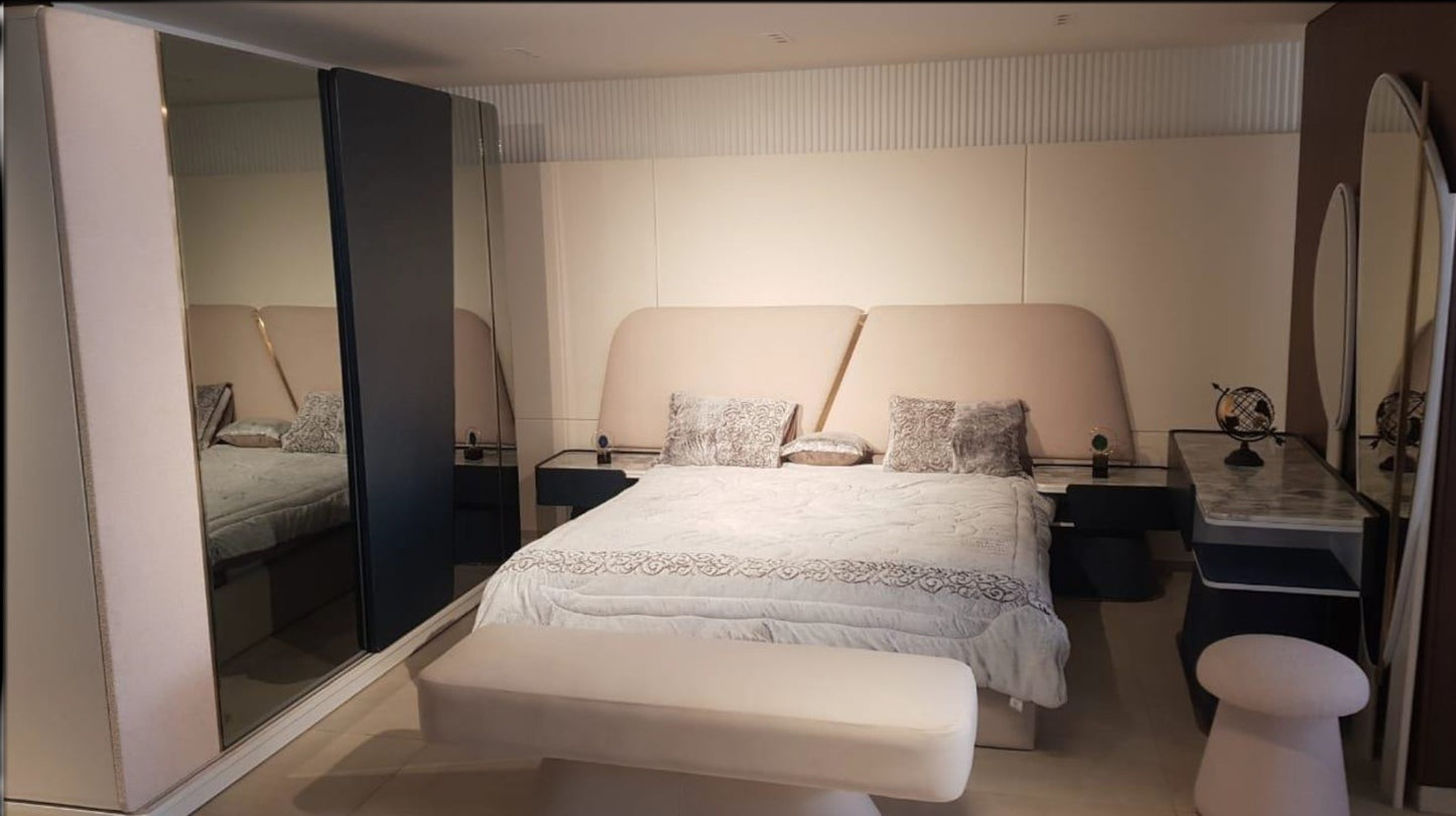 The Nile Luxuries modern bedroom set with upholstered headboard, neutral tones, gold accent, and mirrored wardrobe.